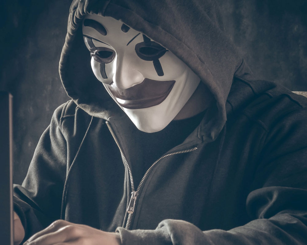 Man in clown mask at computer